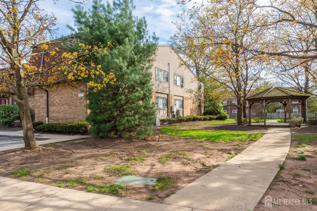 a view of a white house next to a road and yard