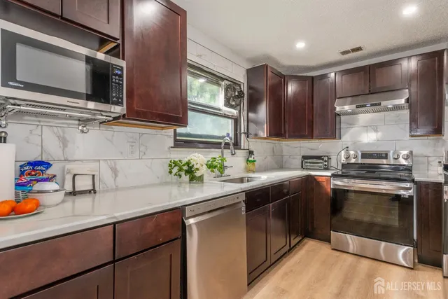a kitchen with stainless steel appliances granite countertop a sink stove and microwave