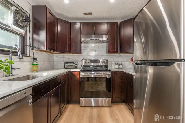 a kitchen with stainless steel appliances granite countertop a sink a stove and a refrigerator