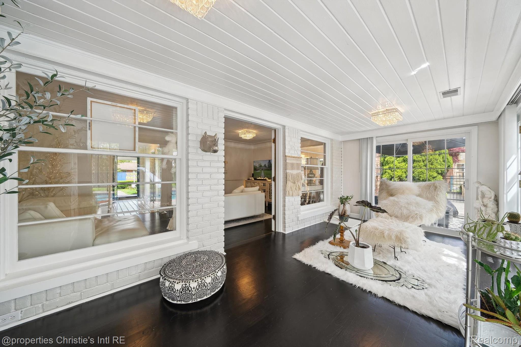 511 South Gulley Road Dearborn, MI 48124 - Photo 26 of 43 Dark wood-finish flooring, white paneled ceiling, white brick wall accents, large multi-pane windows, and sliding glass doors