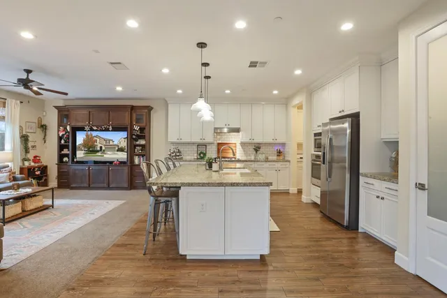 a kitchen with stainless steel appliances granite countertop a refrigerator a sink dishwasher a stove and a refrigerator with wooden floor