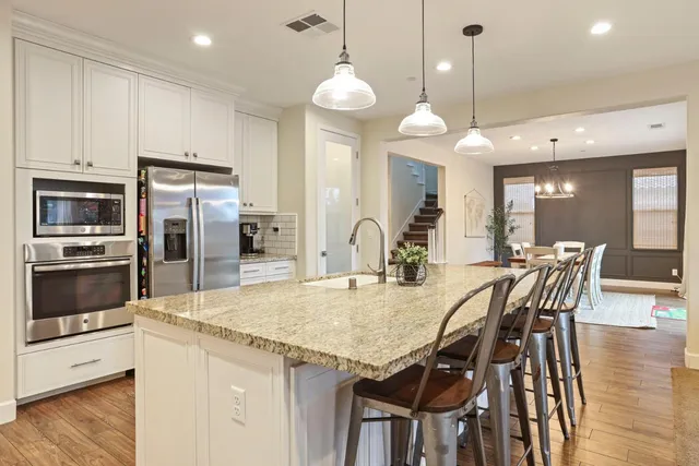 a kitchen with granite countertop a table chairs stainless steel appliances and wooden floor