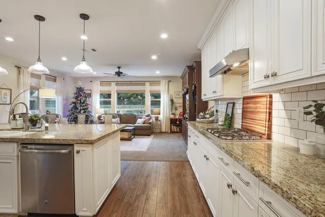 a kitchen with stainless steel appliances granite countertop sink stove and wooden floor