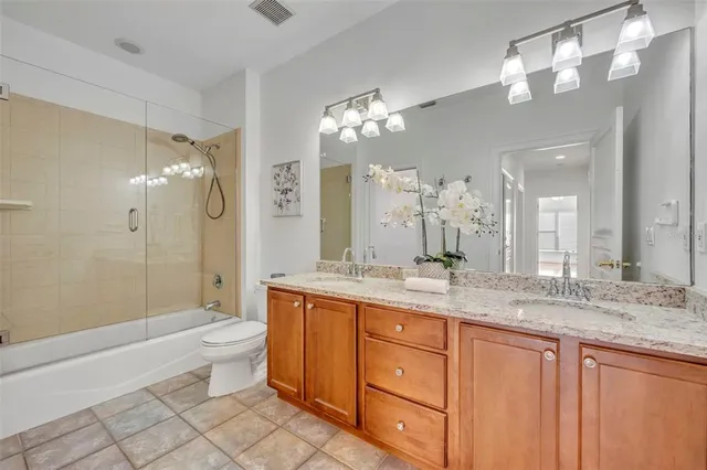 a bathroom with a granite countertop sink a toilet a mirror a bathtub and shower