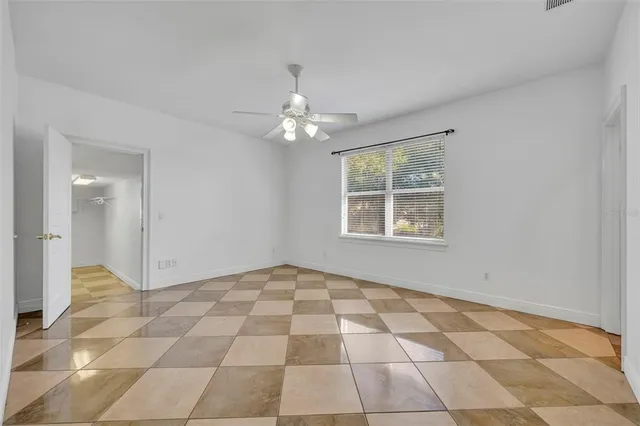 a view of an empty room with windows and chandelier fan