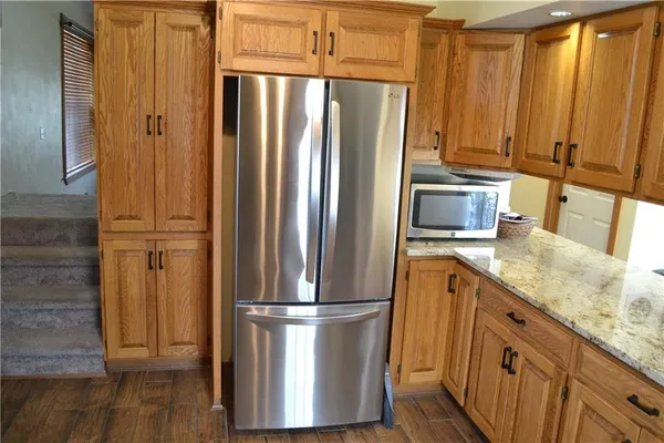 a kitchen with stainless steel appliances granite countertop a refrigerator a stove and a sink with wooden floor