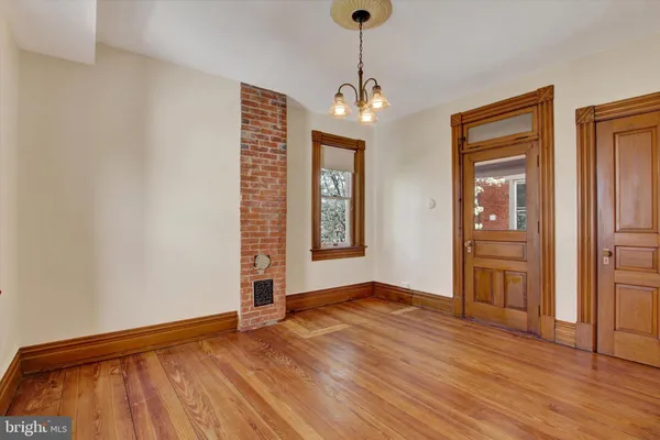 a view of an empty room with window and wooden floor