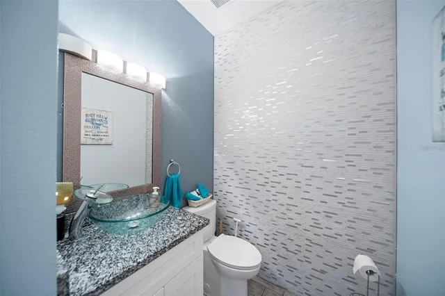 a bathroom with a granite countertop sink a toilet and a mirror