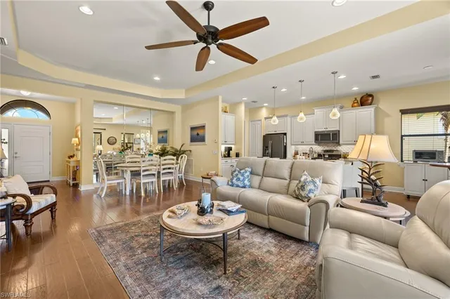a living room with furniture kitchen view and a wooden floor