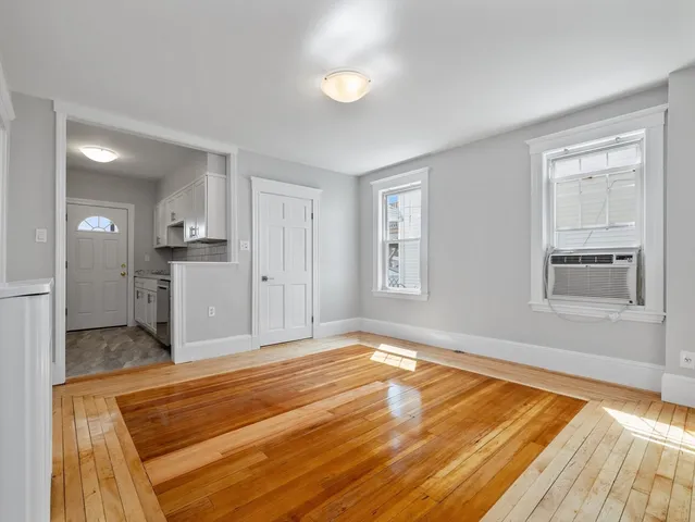 a view of empty room with kitchen and window