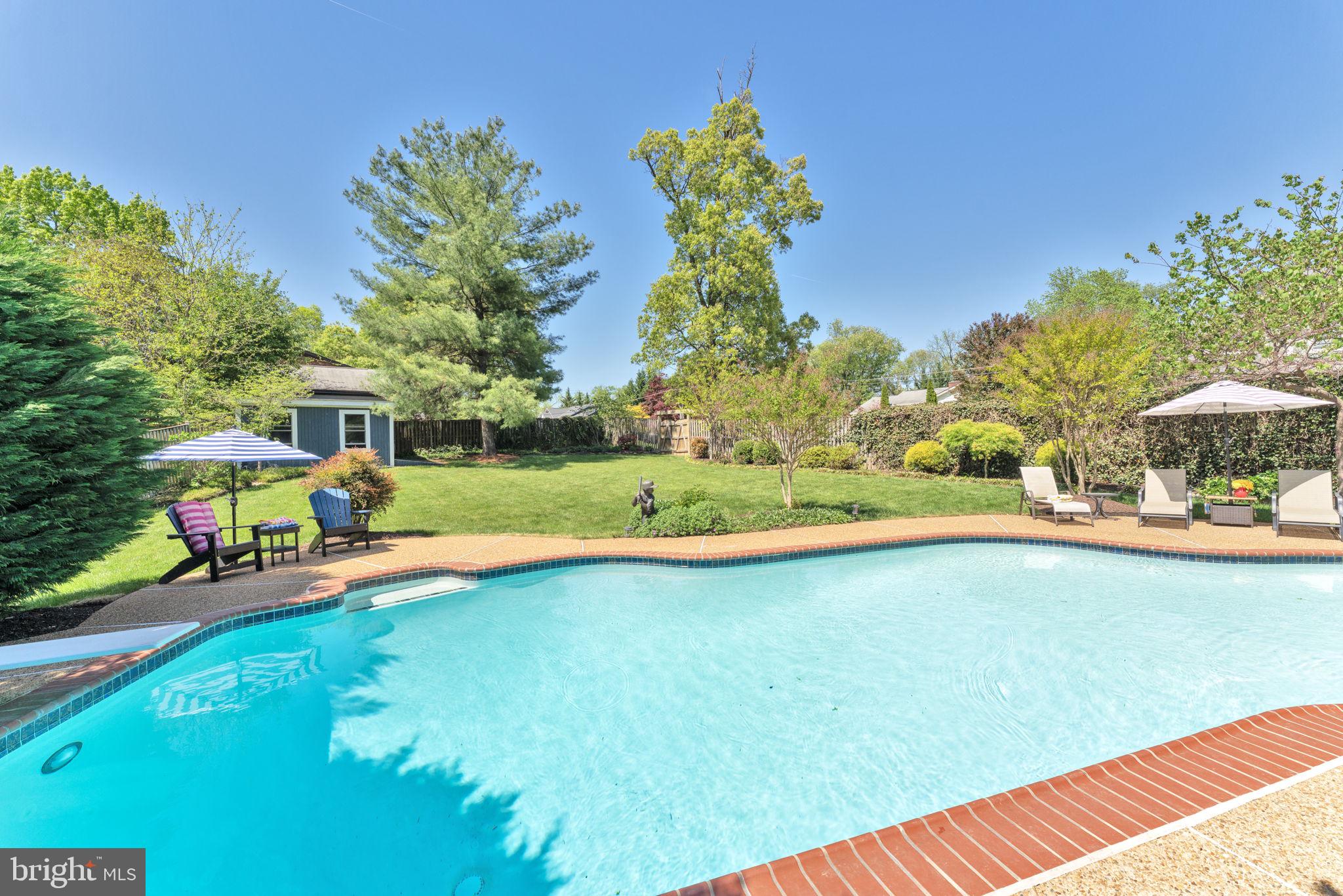 501 Ridge Road Southwest Vienna, VA 22180 - Photo 19 of 54 a view of a swimming pool with a lawn chairs under an umbrella
