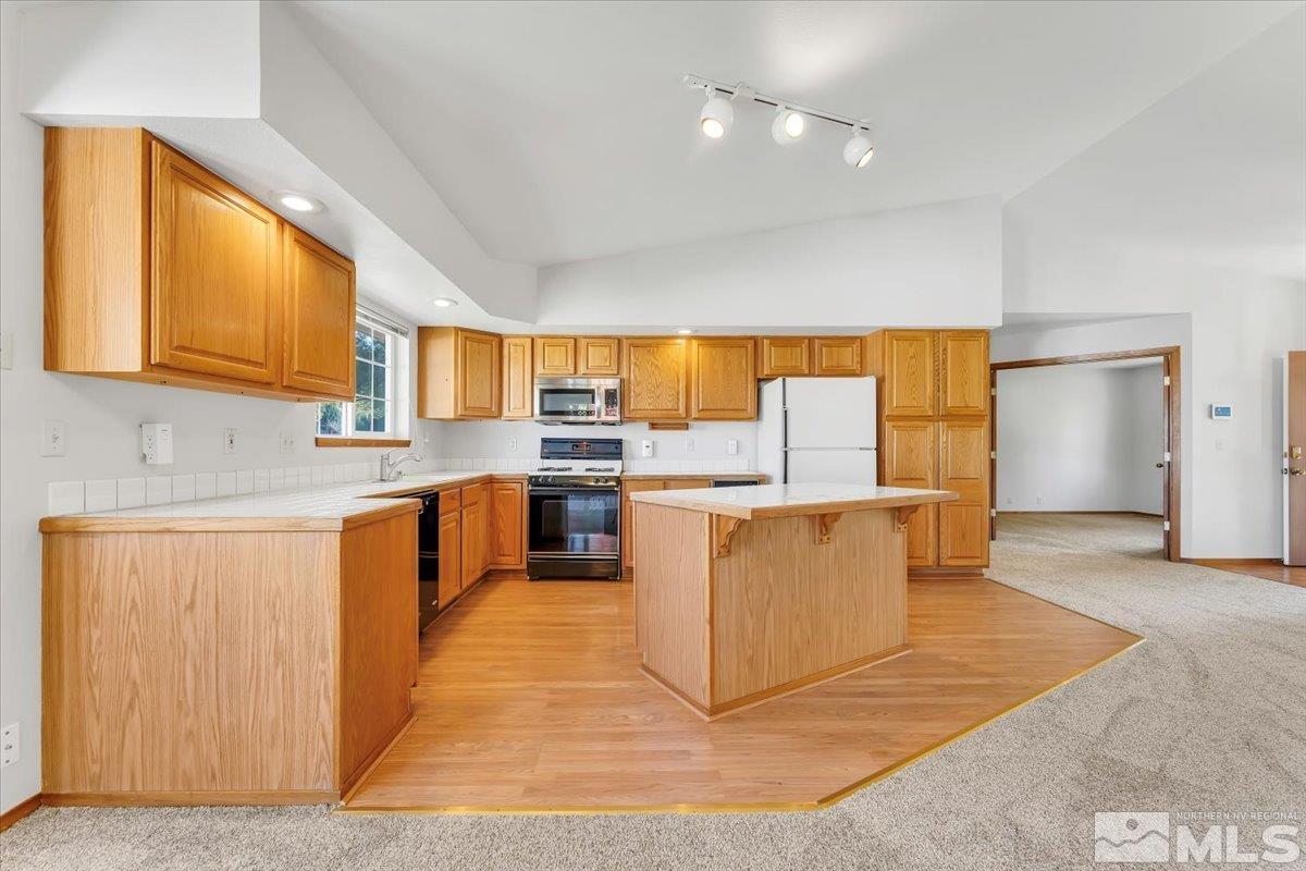 155 Andrew Lane Reno, NV 89521 - Photo 7 of 35 a kitchen with stainless steel appliances granite countertop a stove top oven a sink dishwasher and white cabinets with wooden floor