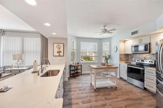 a kitchen with stainless steel appliances kitchen island granite countertop a refrigerator and a stove top oven