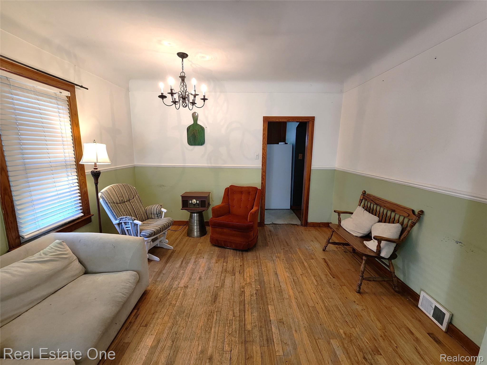 2153 Wiltshire Road Berkley, MI 48072 - Photo 6 of 18 Hardwood flooring throughout the main room, featuring a classic chandelier with candle-style lights