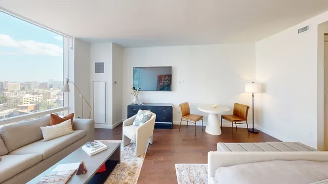 a living room with furniture wooden floor and a large window