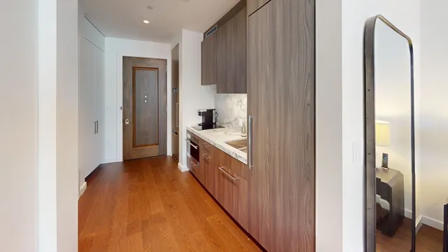 a hallway with stainless steel appliances granite countertop a sink and a refrigerator