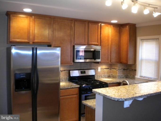 812 Wicklow Road Baltimore, MD 21229 - Photo 1 of 30 a kitchen with granite countertop wooden cabinets a sink stainless steel appliances and a window
