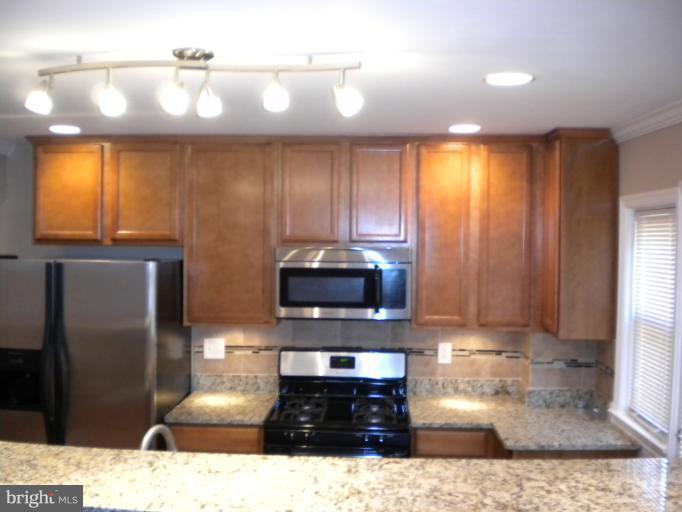 812 Wicklow Road Baltimore, MD 21229 - Photo 18 of 30 a kitchen with stainless steel appliances kitchen island granite countertop a stove a sink and a microwave