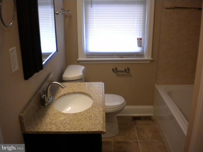 812 Wicklow Road Baltimore, MD 21229 - Photo 29 of 30 a bathroom with a granite countertop sink toilet and mirror