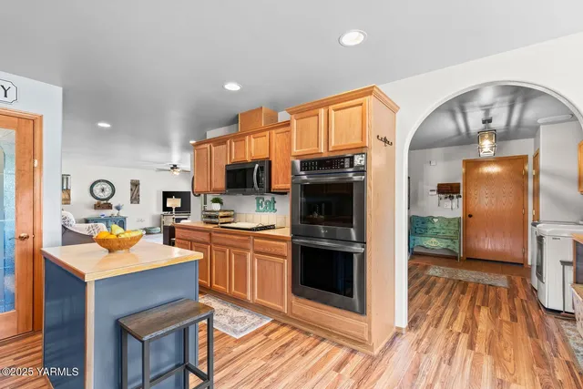 a kitchen with stainless steel appliances granite countertop a refrigerator a stove top oven and sink with wooden floor