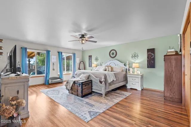 a bedroom with a bed a large window with wooden floor