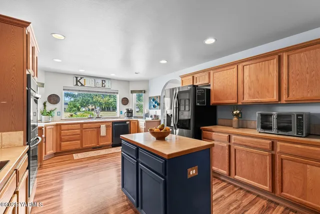 a kitchen with stainless steel appliances granite countertop a stove top oven a refrigerator a sink and dishwasher with wooden floor