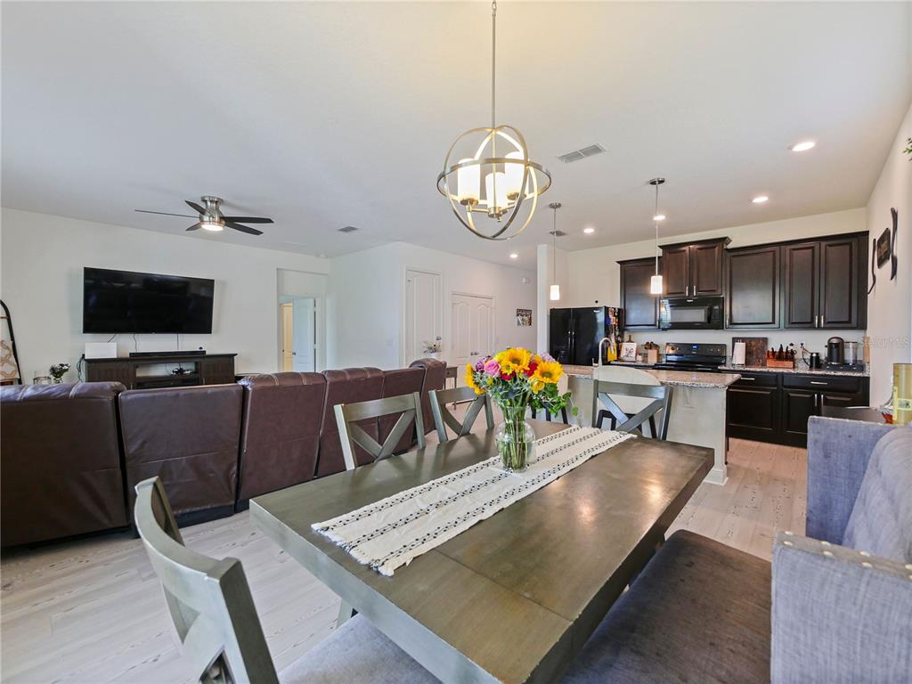 4553 Baler Trails Drive St. Cloud, FL 34772 - Photo 14 of 32 a view of a dining room and livingroom with furniture wooden floor a rug a fireplace and a chandelier