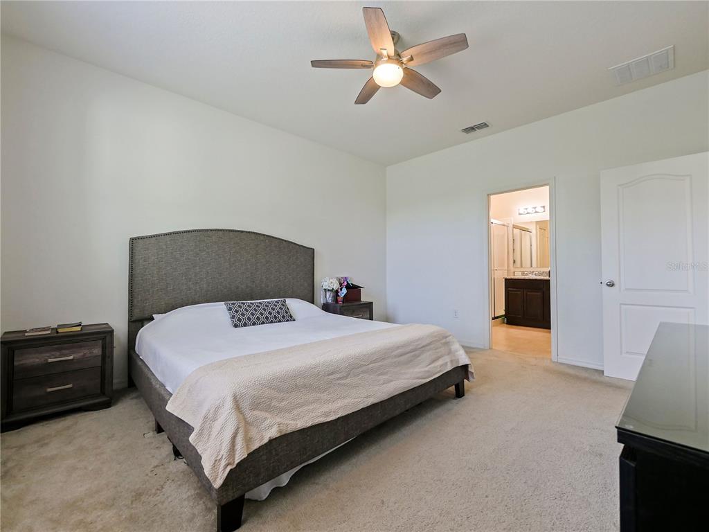 4553 Baler Trails Drive St. Cloud, FL 34772 - Photo 18 of 32 a bedroom with a bed and a ceiling fan