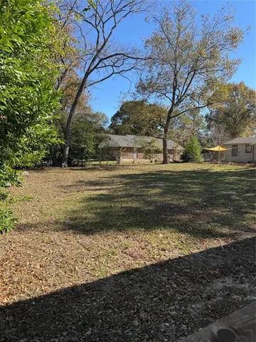 a view of dirt yard with large trees