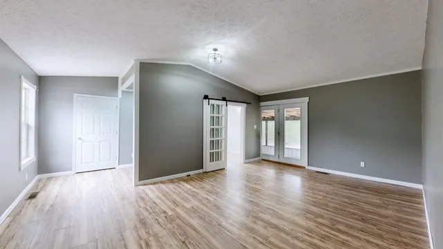 a view of an empty room with window and wooden floor