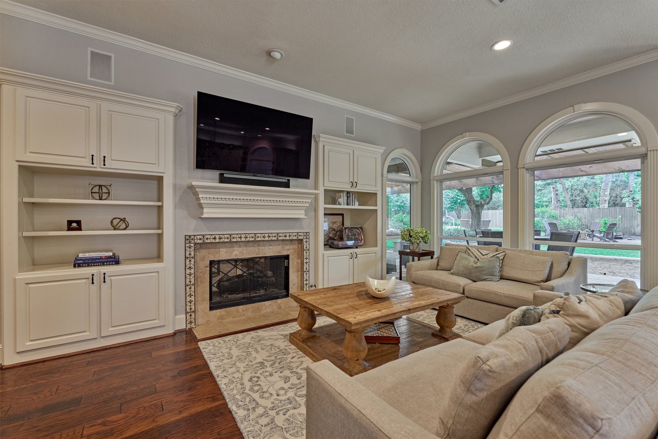18 Treevine Court The Woodlands, TX 77381 - Photo 12 of 50 Built-ins flank the fireplace in the den, offering ample space for media equipment and abundant natural light through the arched windows.