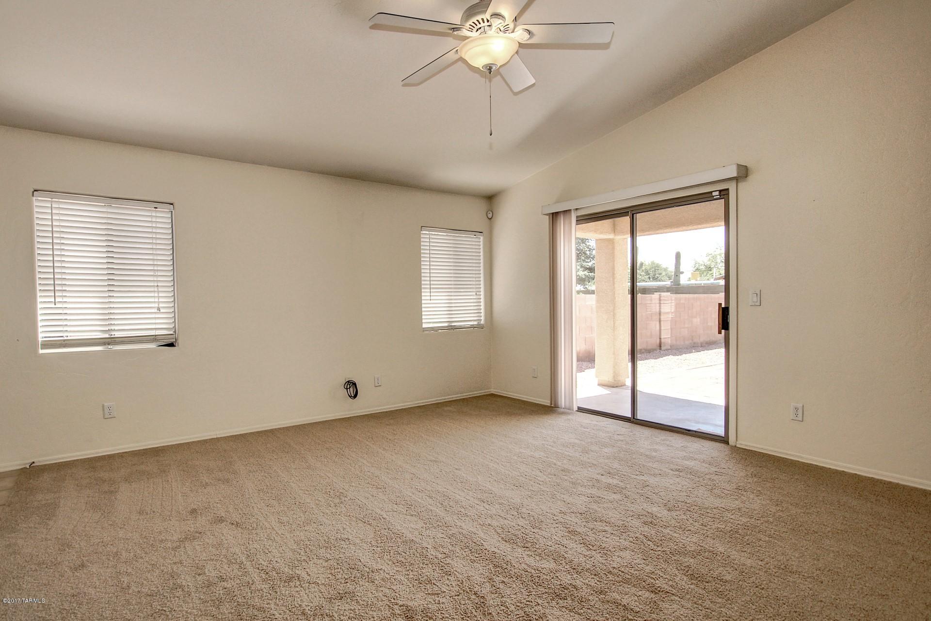 8350 East Bowline Road Tucson, AZ 85710 - Photo 8 of 26 an empty room with chandelier fan and windows