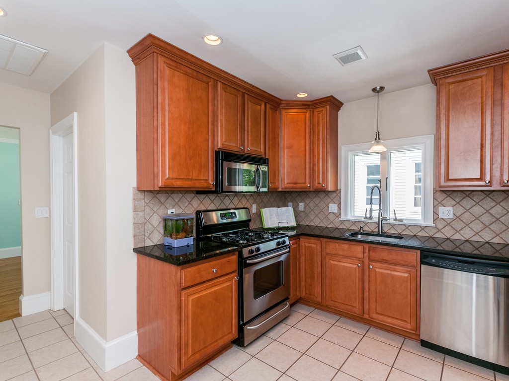 15 Banks Street, Unit 4 Waltham, MA 02451 - Photo 9 of 19 a kitchen with stainless steel appliances granite countertop a stove a sink and a microwave