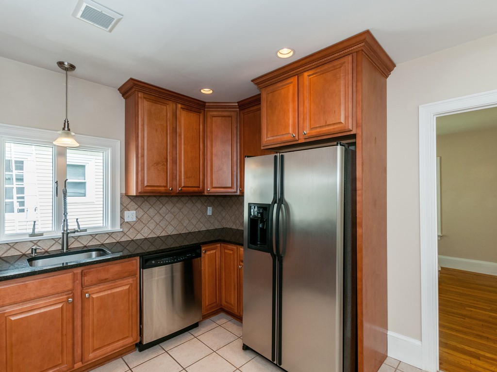 15 Banks Street, Unit 4 Waltham, MA 02451 - Photo 10 of 19 a kitchen with stainless steel appliances granite countertop a refrigerator a sink dishwasher with granite countertops and cabinets next to a window