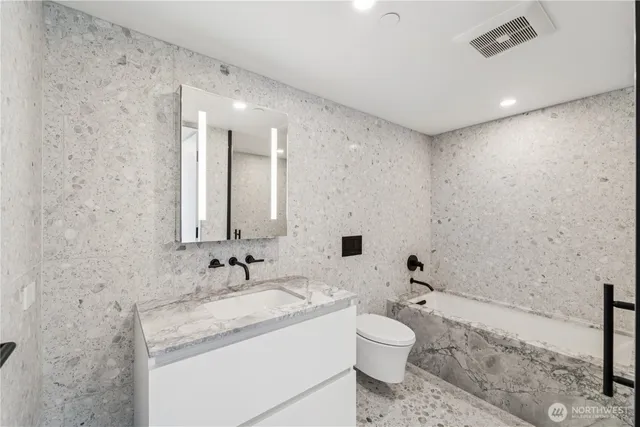 a bathroom with a granite countertop sink a toilet and shower