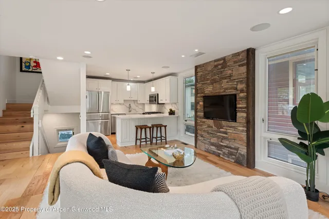 a kitchen with stainless steel appliances granite countertop a stove a refrigerator a microwave a sink and white cabinets with wooden floor