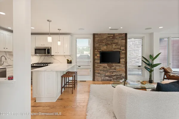 a kitchen with stainless steel appliances kitchen island granite countertop a refrigerator a stove a sink dishwasher and white cabinets with wooden floor