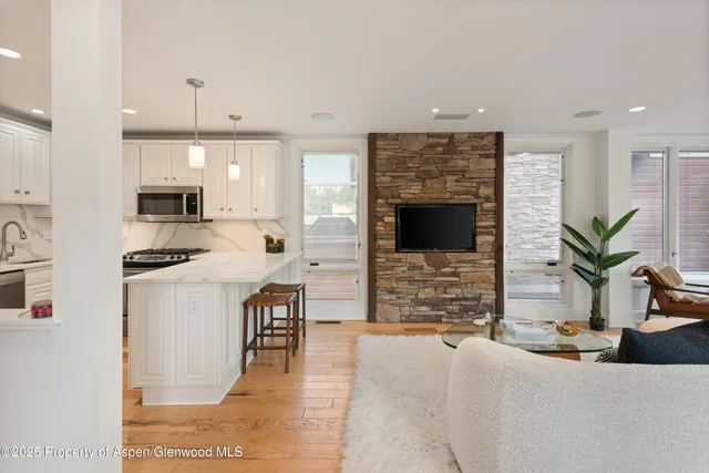 a kitchen with stainless steel appliances kitchen island granite countertop a refrigerator a stove a sink dishwasher and white cabinets with wooden floor