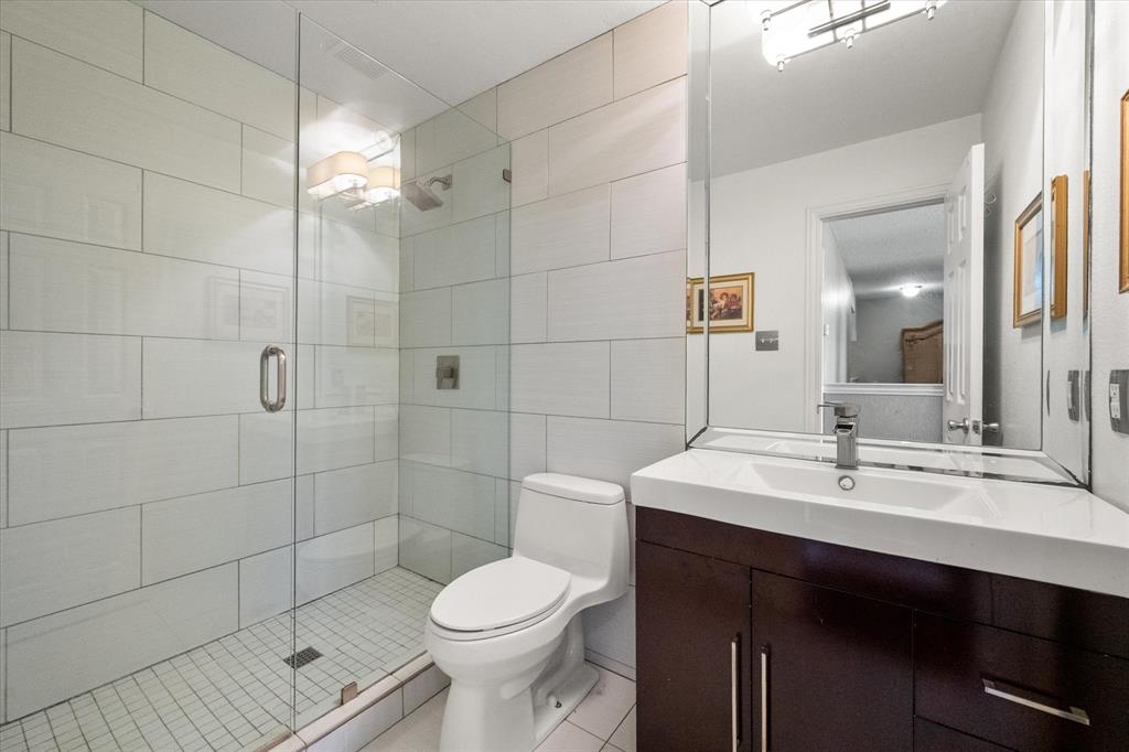 1305 Liverpool Lane Mansfield, TX 76063 - Photo 28 of 40 Bathroom featuring a glass-enclosed shower with white tiled walls, a vanity with a dark wood finish and a white sink, and a large mirror