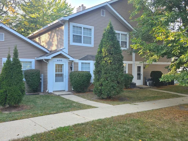 a front view of a house with a yard and potted plants