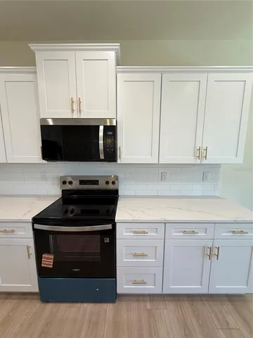 a kitchen with white cabinets and black appliances