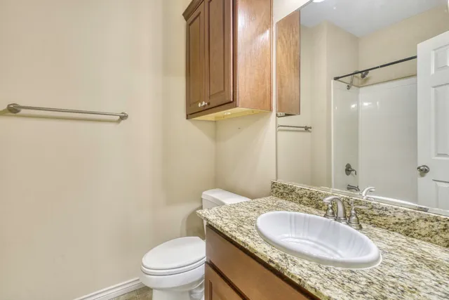 a bathroom with a granite countertop sink a toilet and a mirror