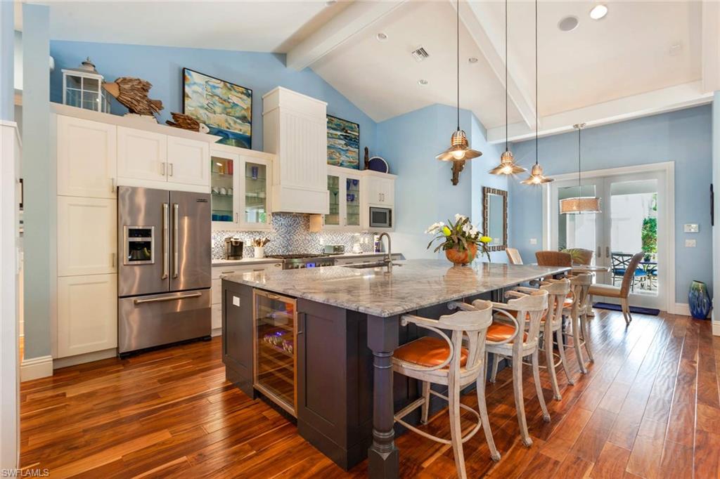 150 Central Avenue Naples, FL 34102 - Photo 8 of 34 a kitchen with stainless steel appliances granite countertop a kitchen island wooden floors and white cabinets