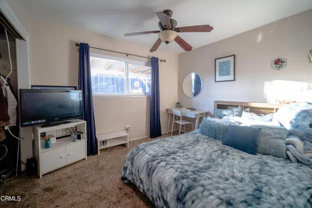 a bedroom with a bed and a flat tv screen on dresser