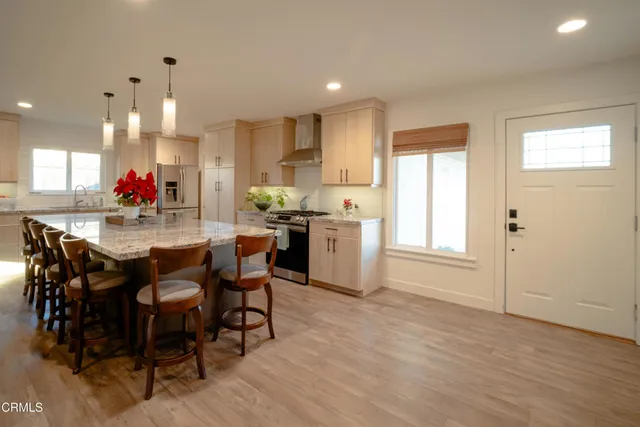 a kitchen with stainless steel appliances a dining table chairs and wooden floor
