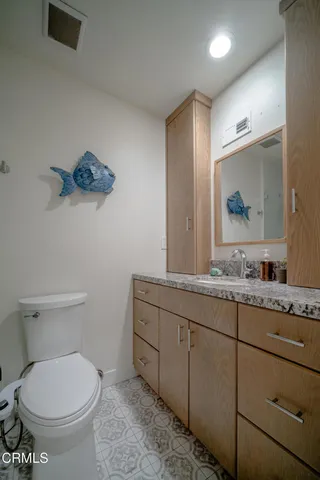 a bathroom with a granite countertop toilet sink and mirror