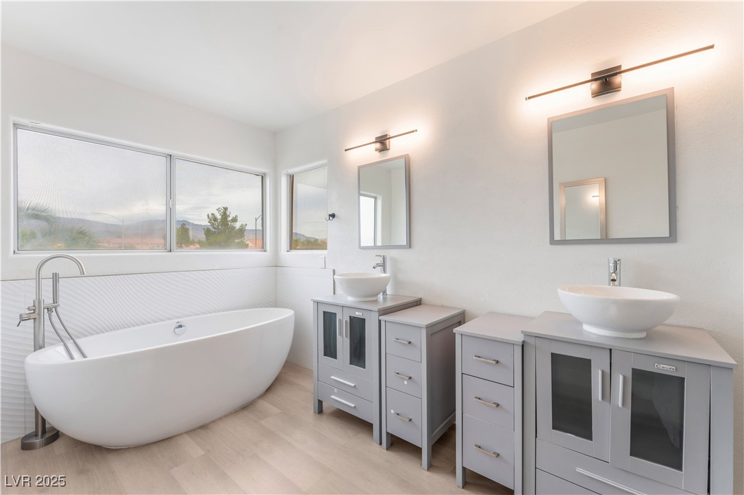 3695 Funston Way Las Vegas, NV 89129 - Photo 3 of 43 Bathroom with two vanities, light wood-type flooring, and a freestanding tub