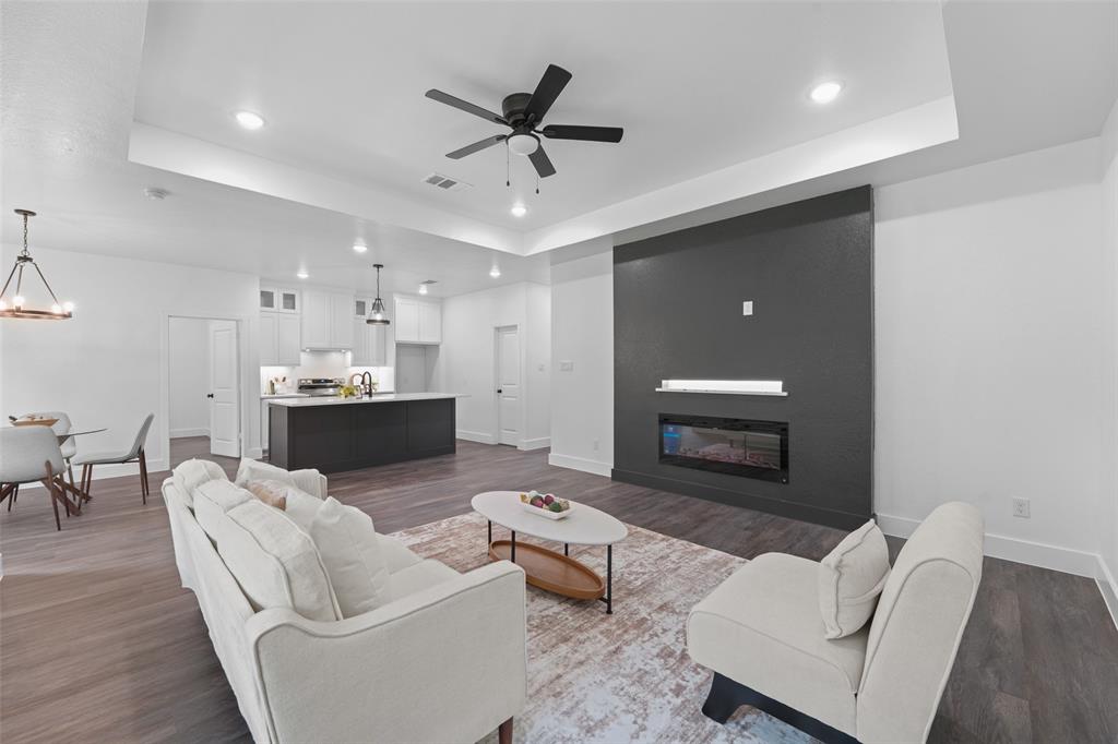 122 East Beachwood Loop Trinidad, TX 75163 - Photo 9 of 35 Open-concept living space featuring wood-finish flooring, a contemporary dark accent wall with an integrated electric fireplace, and recessed lighting