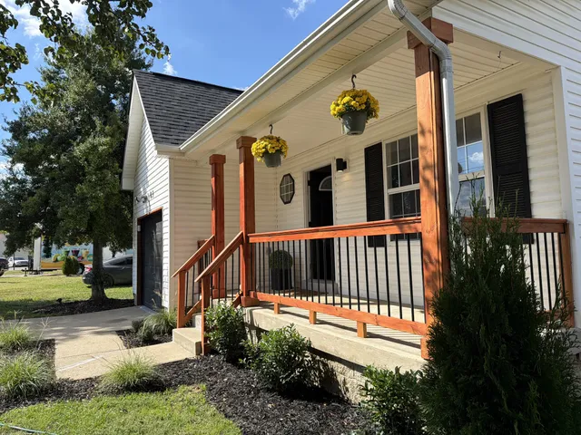 a view of an empty room with wooden floor fireplace and a window
