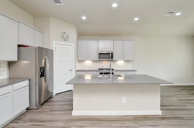 a kitchen with kitchen island stainless steel appliances a sink a stove a refrigerator and cabinets